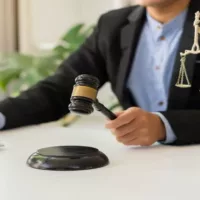 Goddess of Justice with Scales and Hammers Placed in Front of a Male Lawyer Working on a Laptop