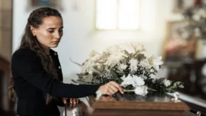Funeral, Sad, and Woman with a Flower on the Coffin After the Loss of a Loved One, Family, or Friend