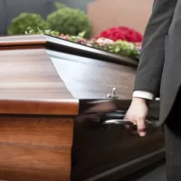 Funeral with a Coffin in a Cemetery, the Casket Carried by Coffin Bearer